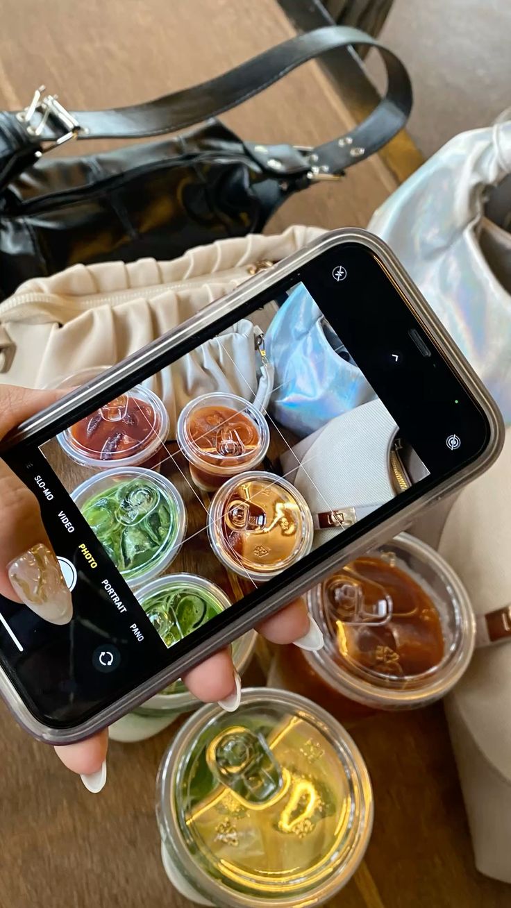 A smartphone capturing a photo of various colorful iced beverages, including matcha and coffee, illustrating the process of creating viral beverage content for social media platforms like TikTok.